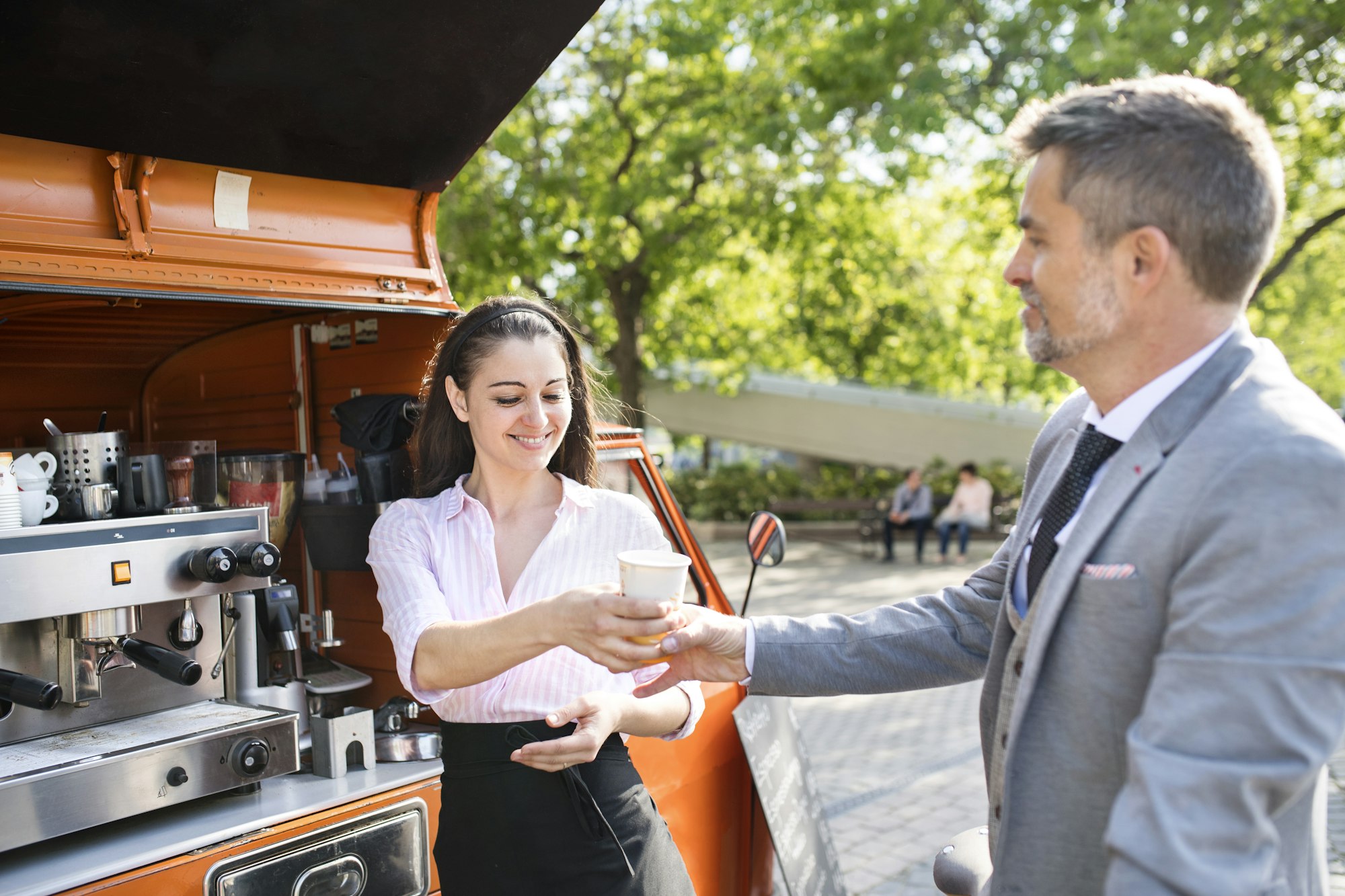 Businessman buying take away coffee on the street