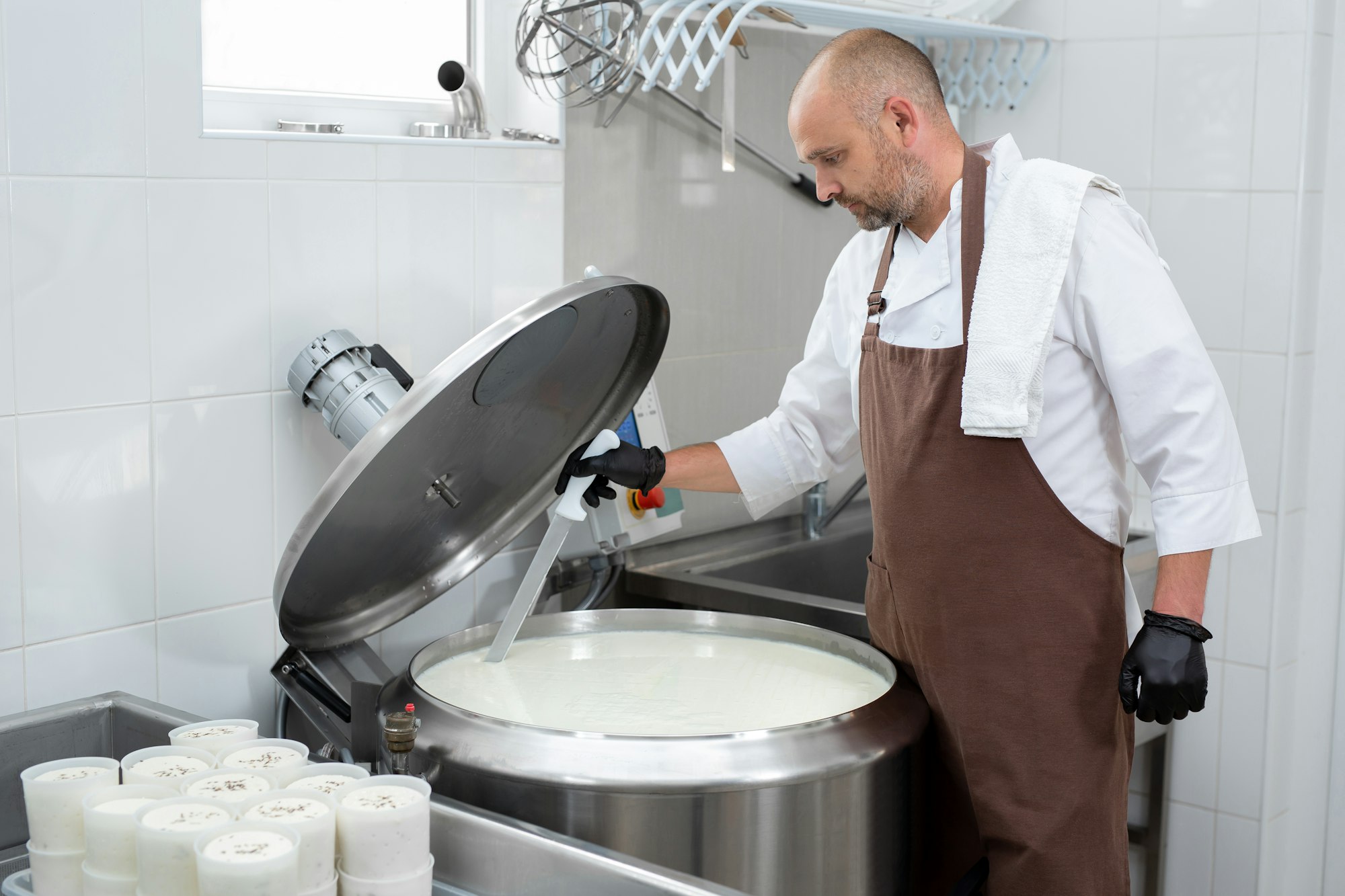 Cooking cheese from a private cheese factory. A man cuts raw materials with a large knife.